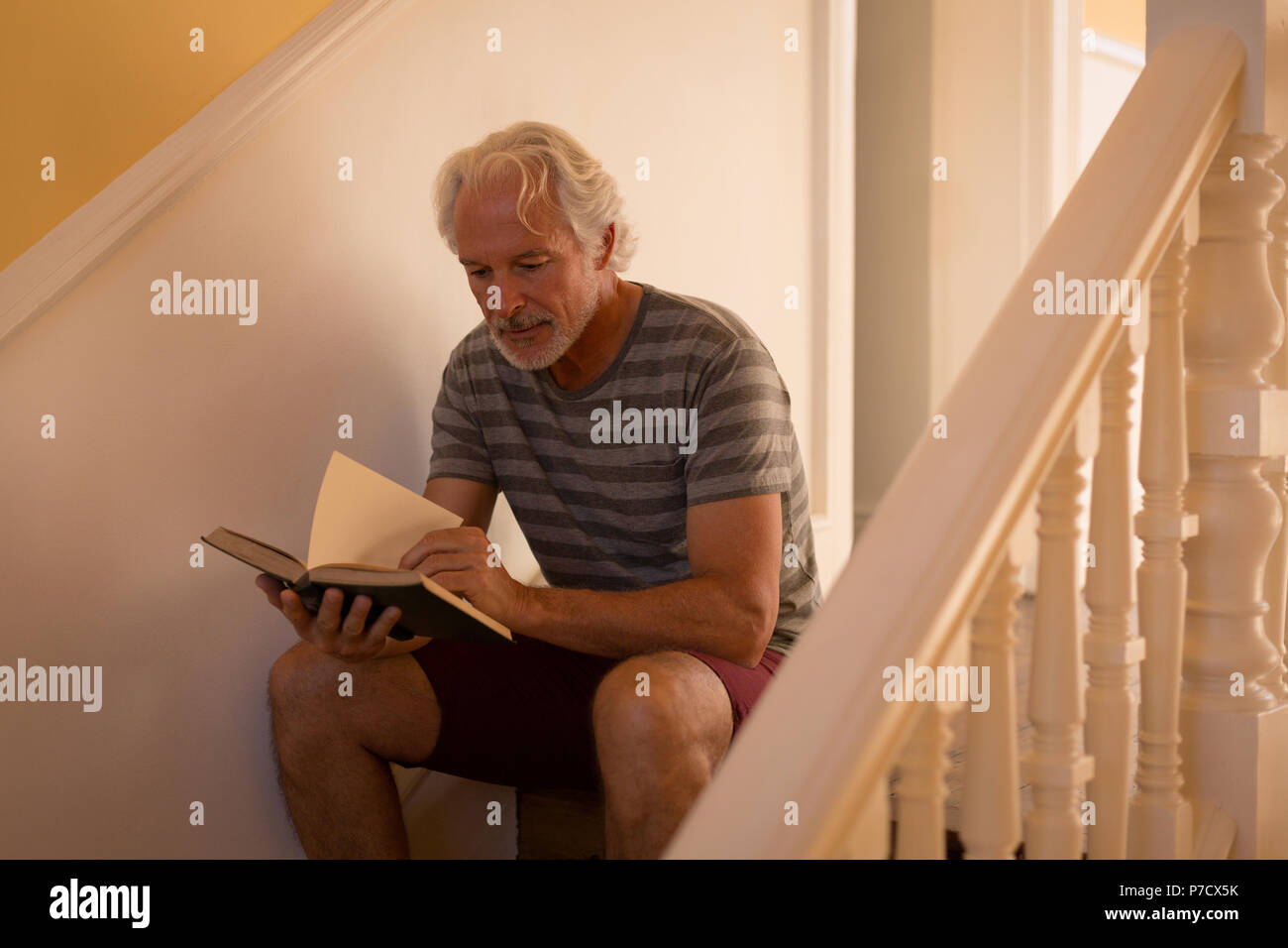 Ältere Menschen mit einem Buch auf der Treppe zu Hause Stockfoto