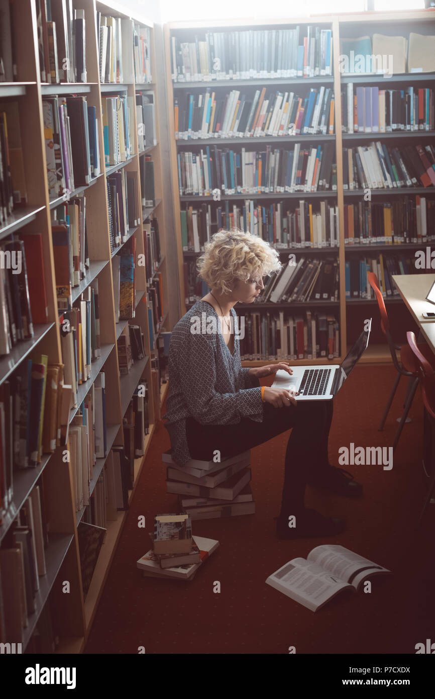 Frau mit Laptop in der Bibliothek Stockfoto