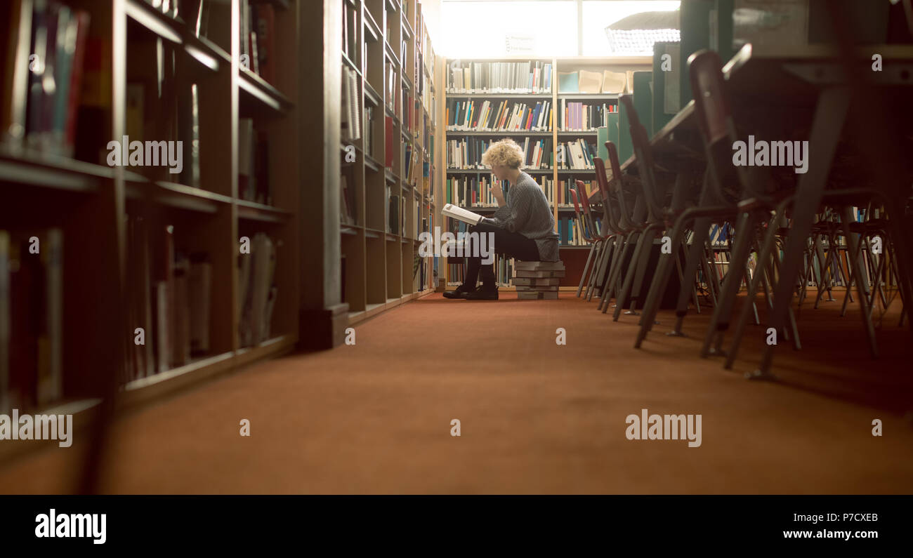 Frau mit einem Buch in der Bibliothek Stockfoto