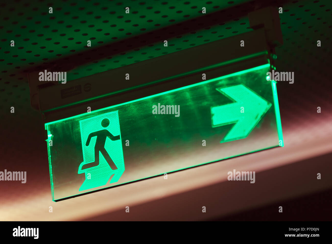 Beleuchtete grüne Notausgang Schild, was darauf hinweist, dass der Fluchtweg ist auf der rechten Seite Stockfoto