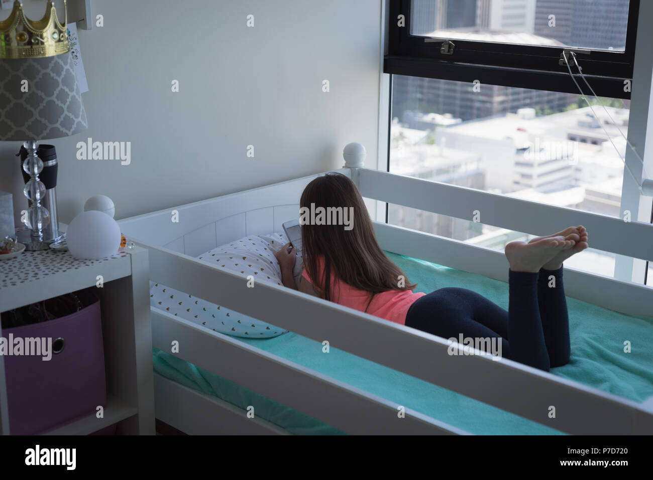 Mädchen mit Handy im Schlafzimmer Stockfoto