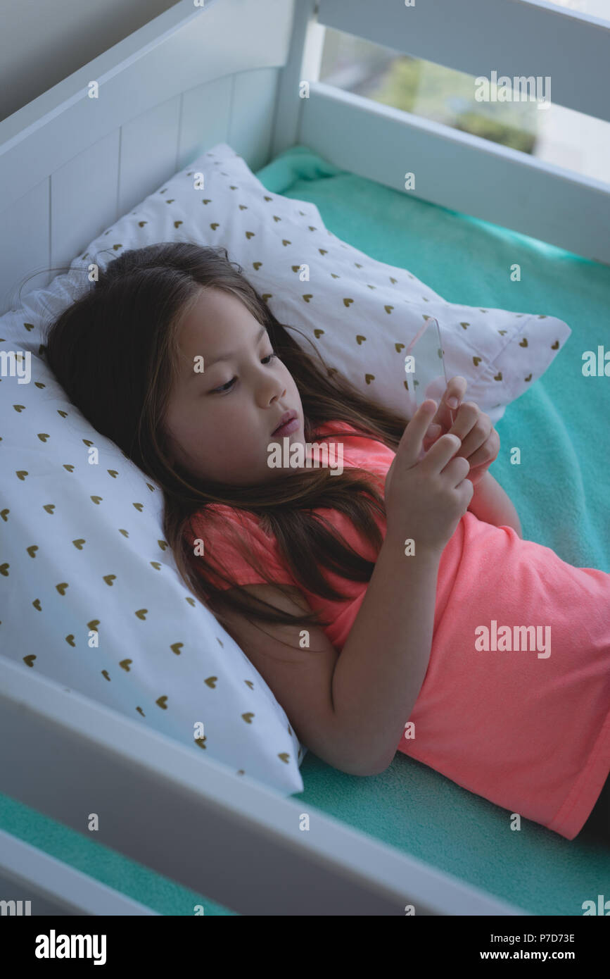 Mädchen mit Glas Mobiltelefon im Schlafzimmer Stockfoto