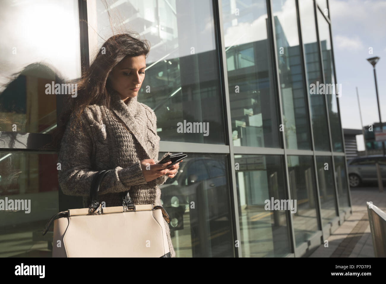 Frau mit Mobiltelefon außerhalb eines Gebäudes Struktur Stockfoto
