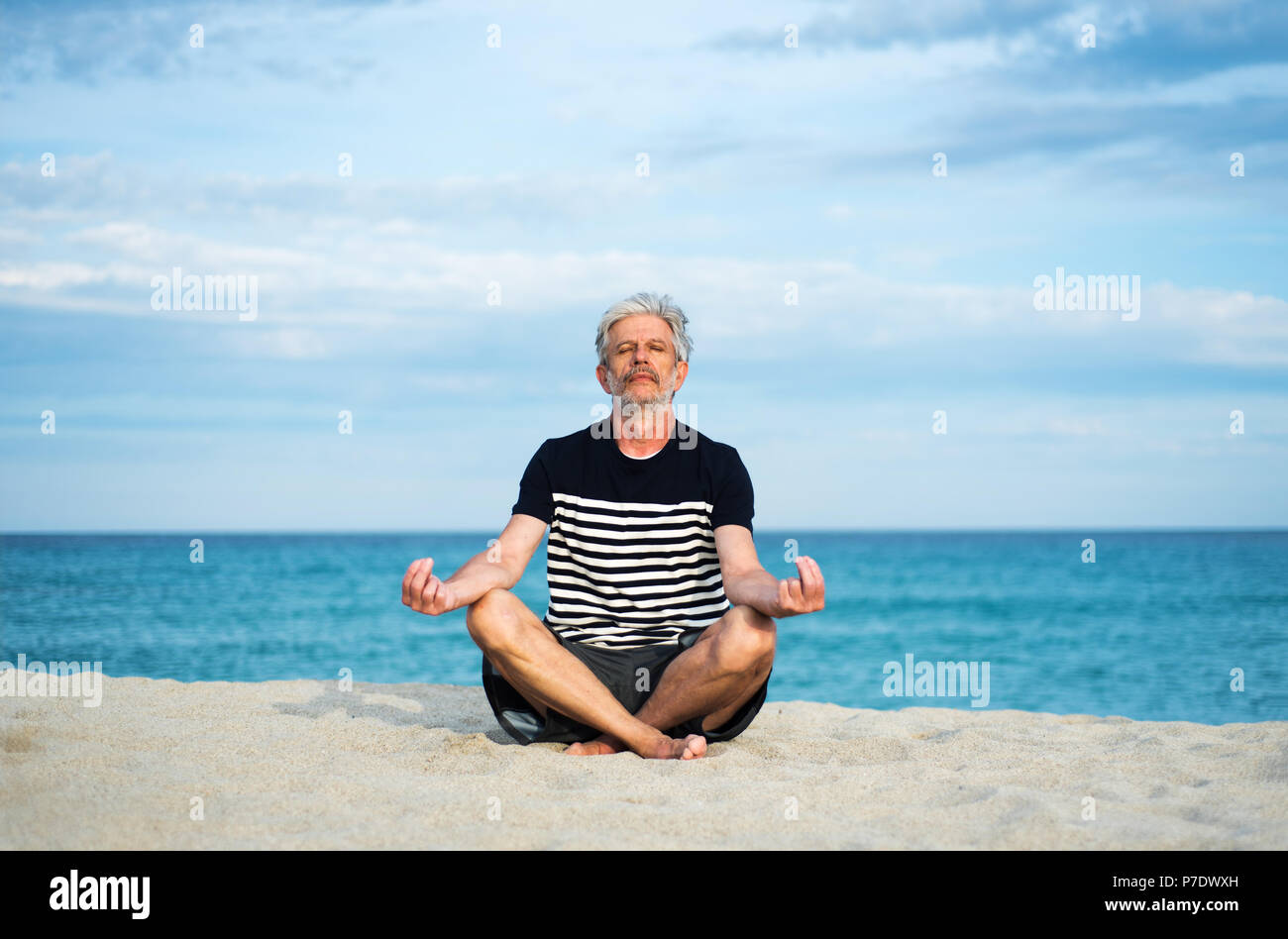 Ältere Menschen meditieren am Strand, Sommerurlaub Workout Stockfoto