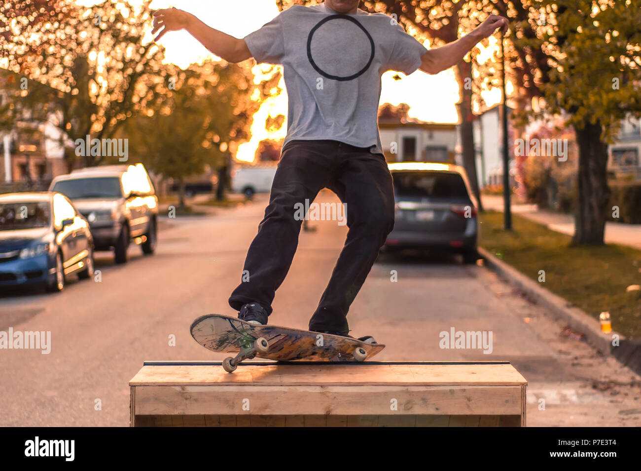 Junge männliche skateboarder Balancing auf der Rampe am Vorstadtstraße bei Sonnenuntergang, Hals nach unten Stockfoto