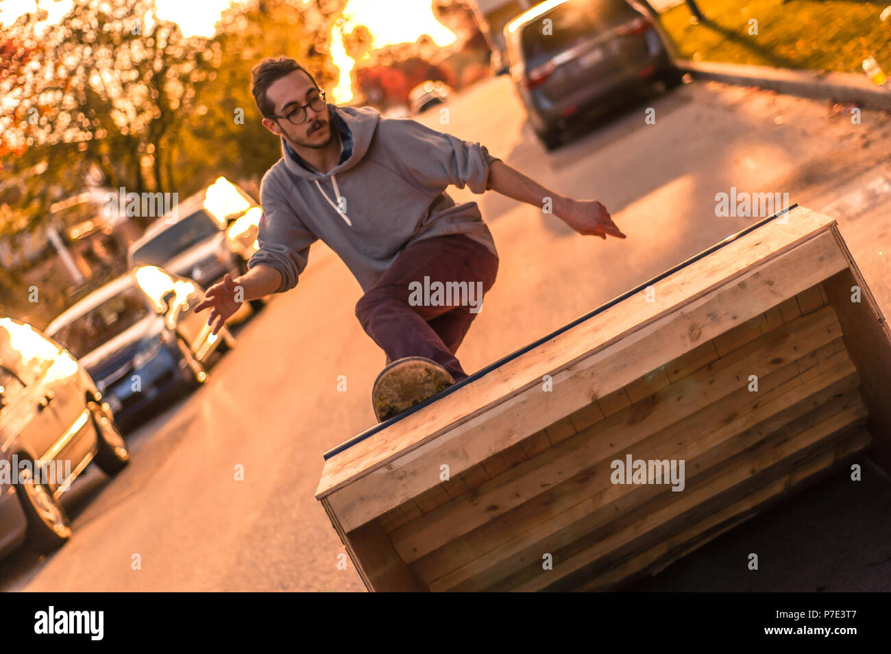 Junge männliche Skateboarder drehen die Rampe auf vorstadtstraße bei Sonnenuntergang Stockfoto