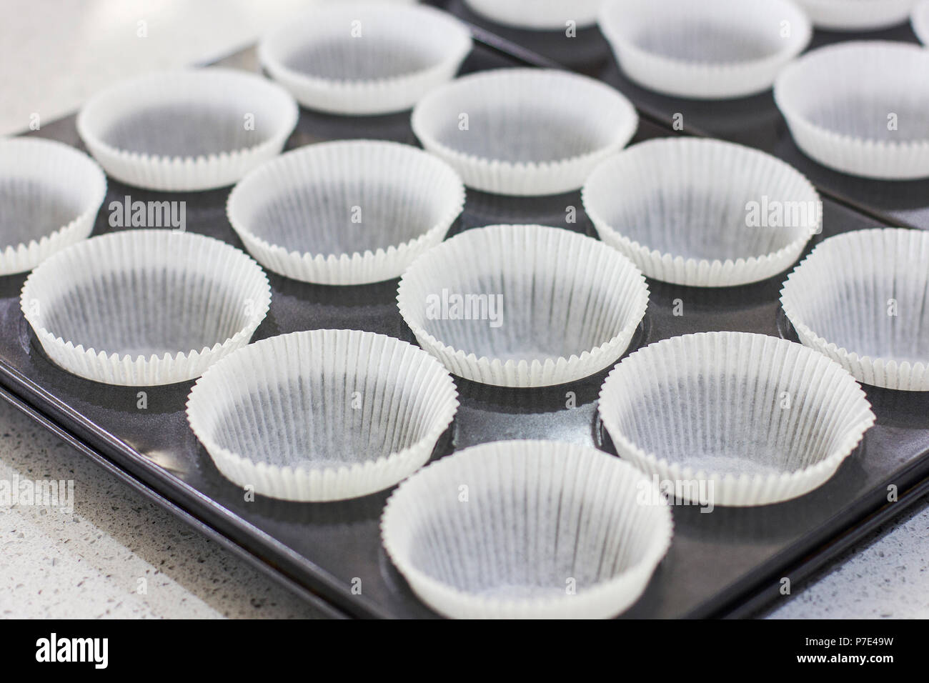 Leere Formulare für Muffins und Kuchen in einem Metallauflagefach Stockfoto