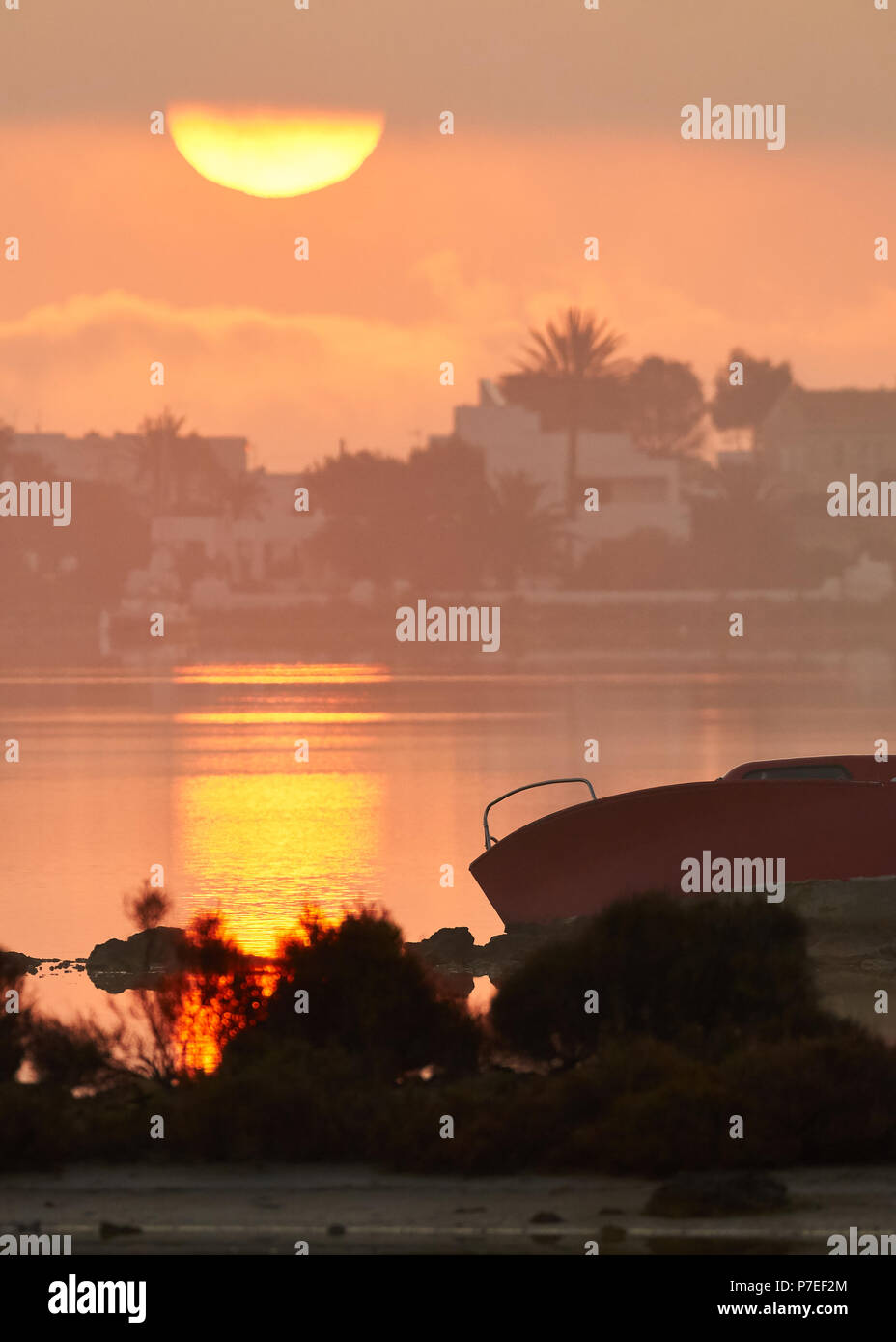 Sonnenaufgang am Estany des Peix marine Lagune mit Boot und Strand La Savina im Hintergrund (Ses Salines Natural Park, Formentera, Balearen) Stockfoto