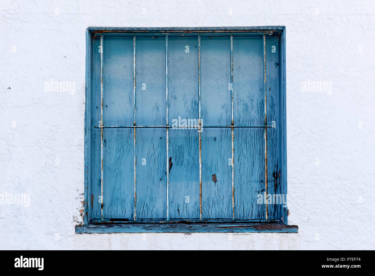 Blaues Quadrat Gitterfenster gegen eine weiße Wand Stockfoto