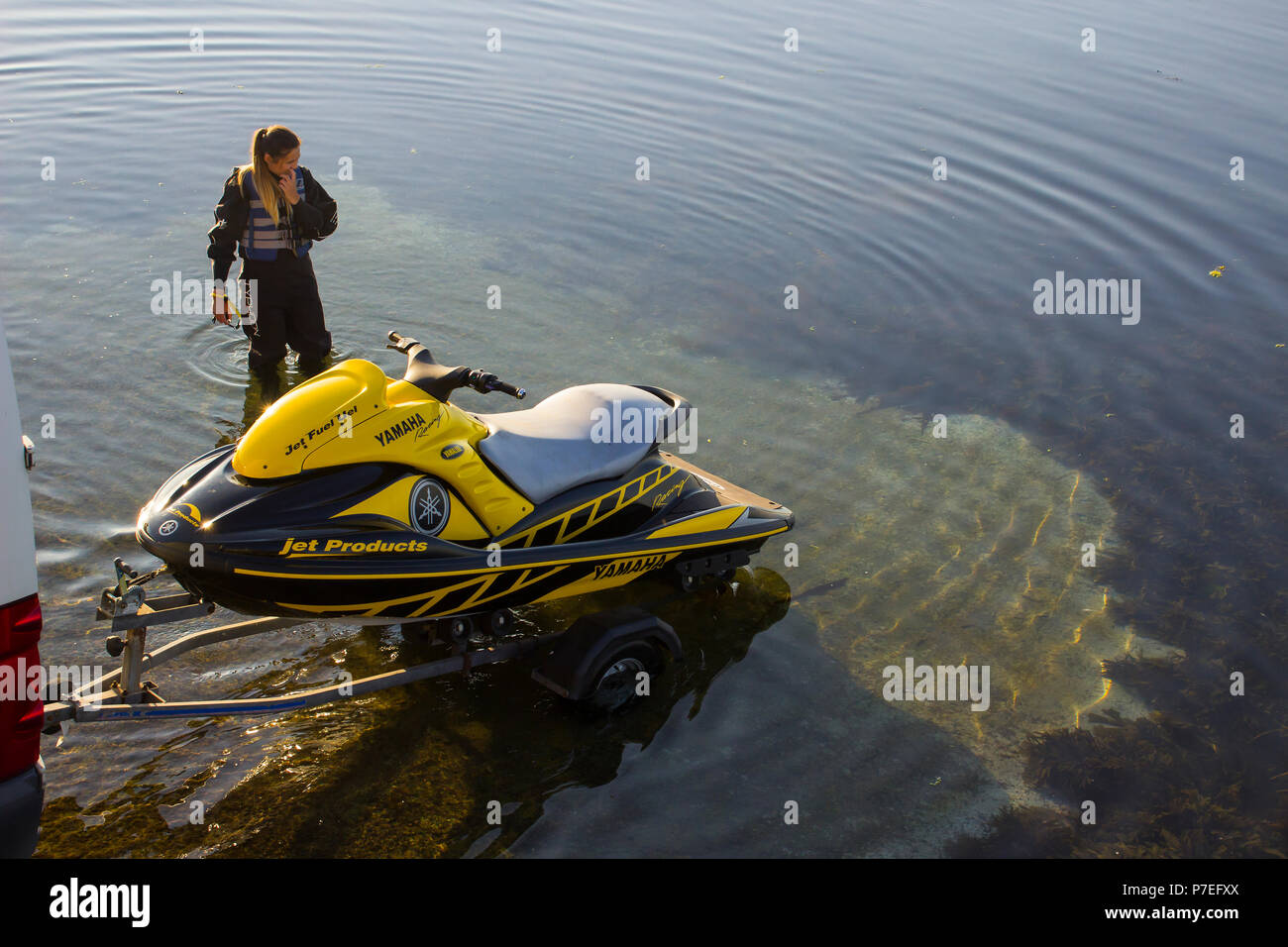 29. Juni 2018 eine junge Frau in einen Taucheranzug wartet auf Ihren Partner neben einem leistungsstarken Yamaha Jet-Ski auf der Helling in Groomsport Hafen Nordirland Stockfoto