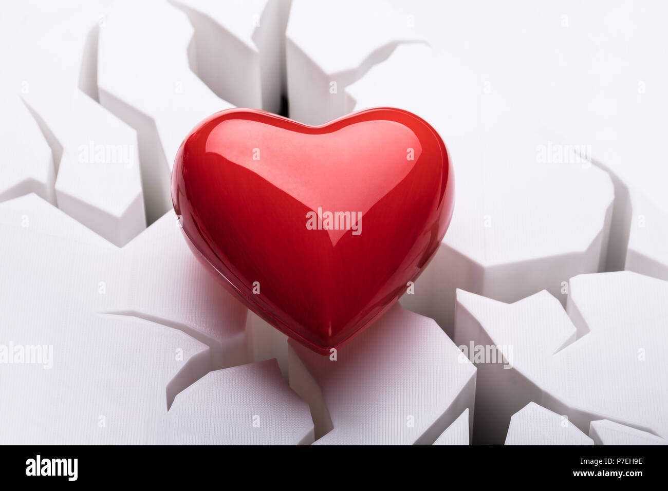 Hohe Betrachtungswinkel von roten Herzen auf Risse im weißen Hintergrund Stockfoto