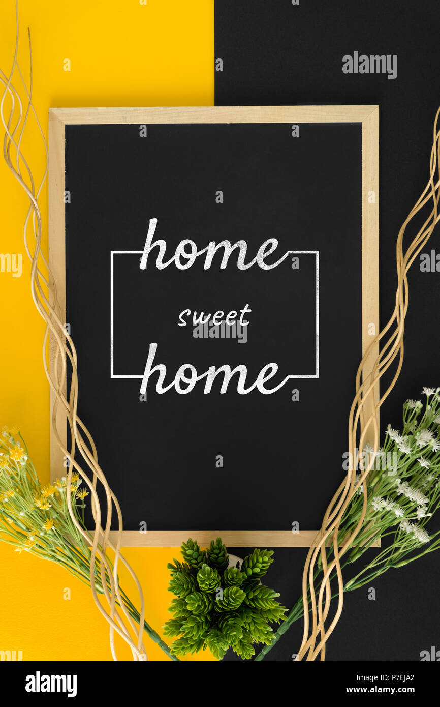 Home sweet home auf schwarzem und gelbem Hintergrund mit rustikalem Holz Sticks und Blume. Stockfoto