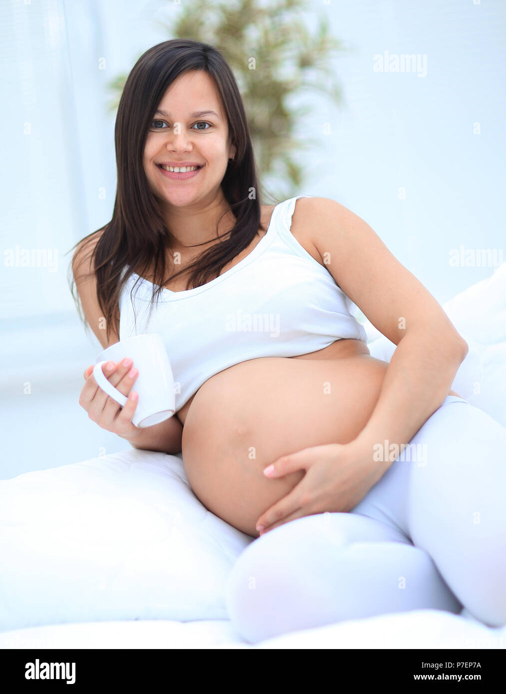 Gerne schwangere Frau im Wohnzimmer sitzen Stockfoto