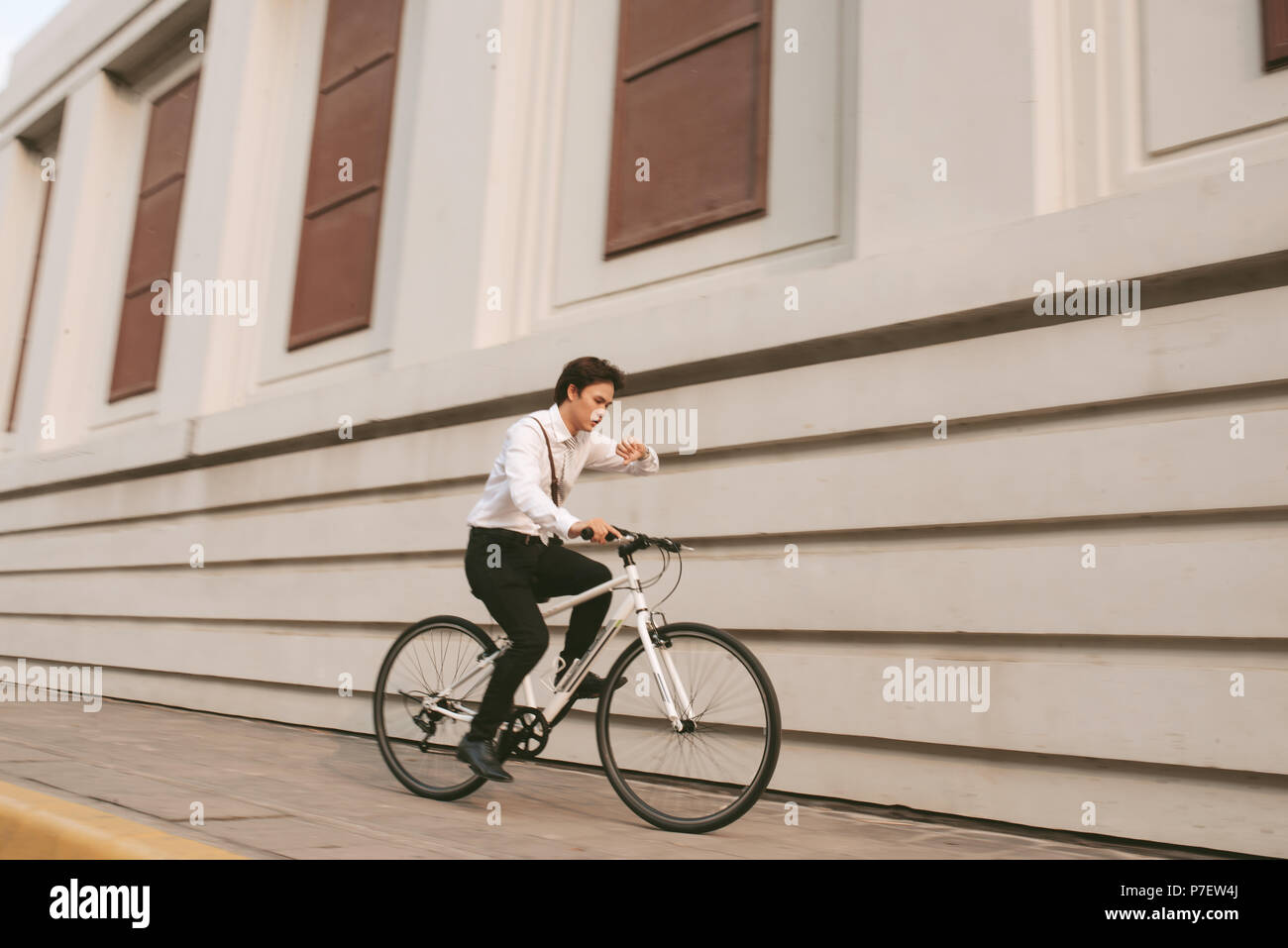 Beeilen Sie sich asiatische Geschäftsmann Reiten Fahrrad im Berufsverkehr. Junger Mann spät für Zug arbeiten, Konferenz. Büro Leben und Geschäft. Stockfoto