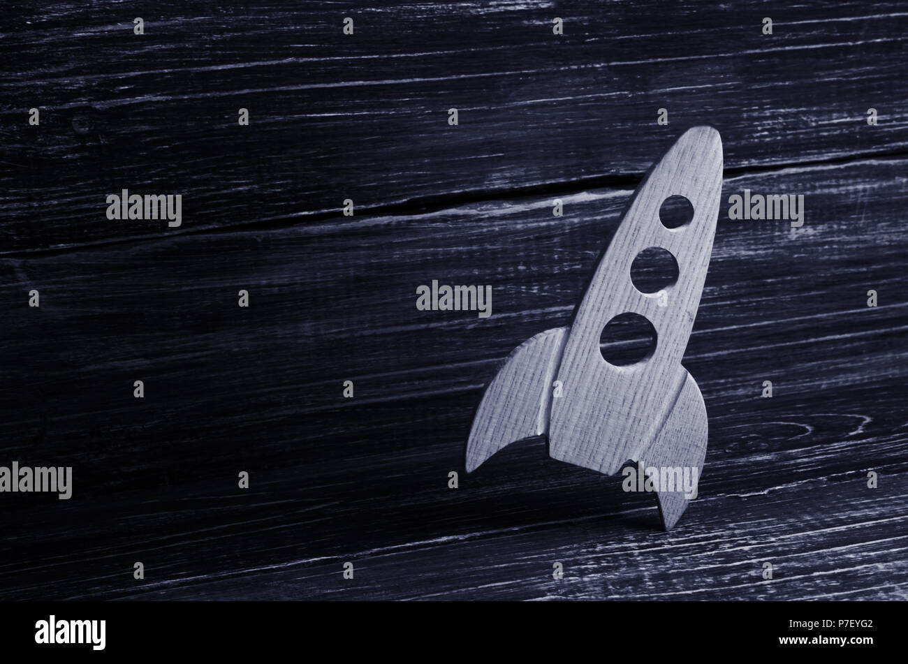 Holz- platz Rakete im Retro Stil liegt auf einem dunklen Hintergrund. Der Raumfahrtindustrie, die Entwicklung der Technik und der Eroberung des Weltraums. Creati Stockfoto