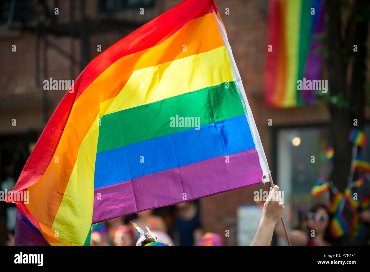 Teilnehmer mit großen, hintergrundbeleuchteten Regenbogen Flagge in die jährliche Gay Pride Parade, wie es durch Greenwich Village. Stockfoto