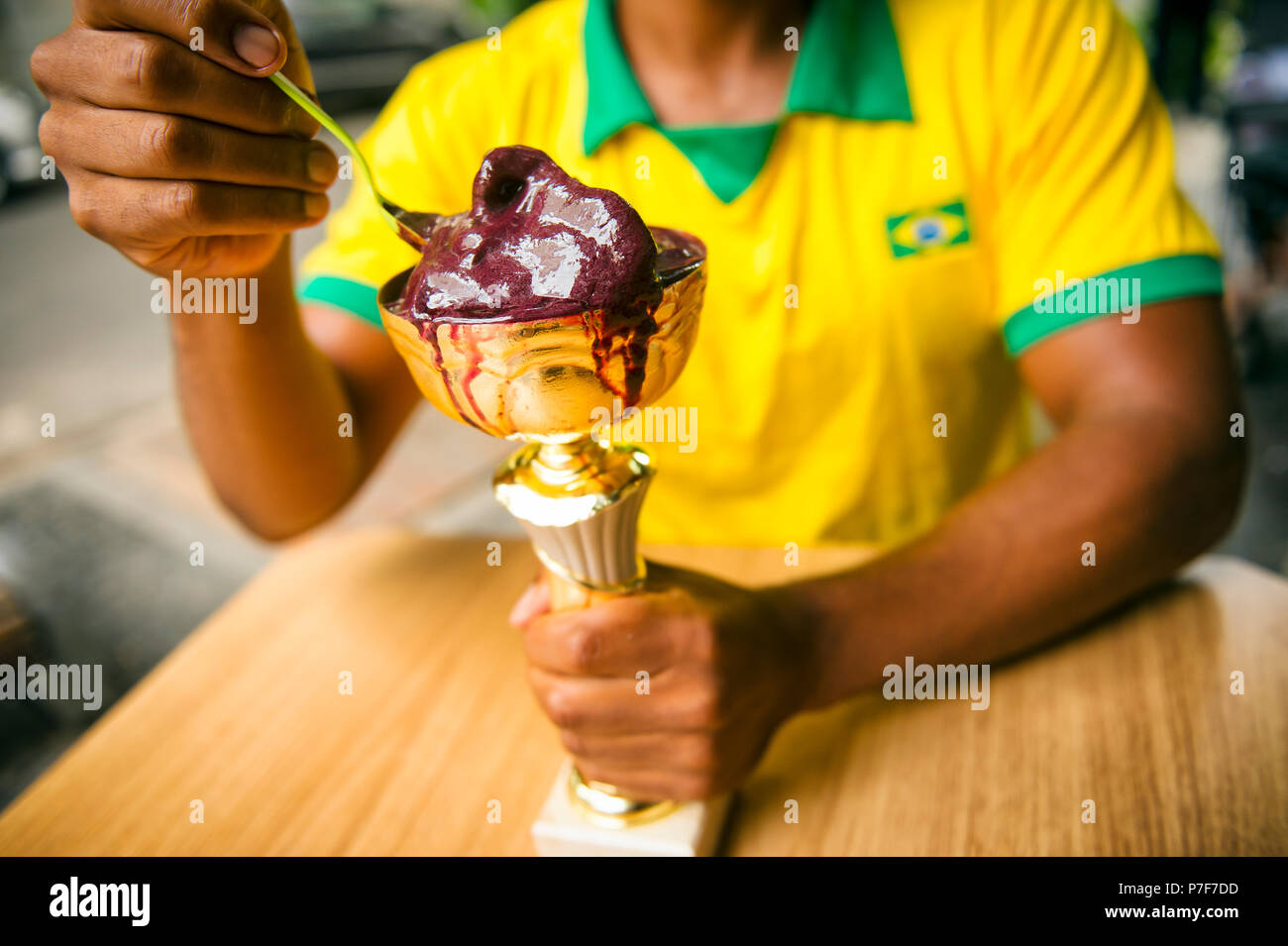 Brasilianische Athleten mit Vintage flag Shirt feiert Sieg mit einer Trophäe voller Acai Stockfoto