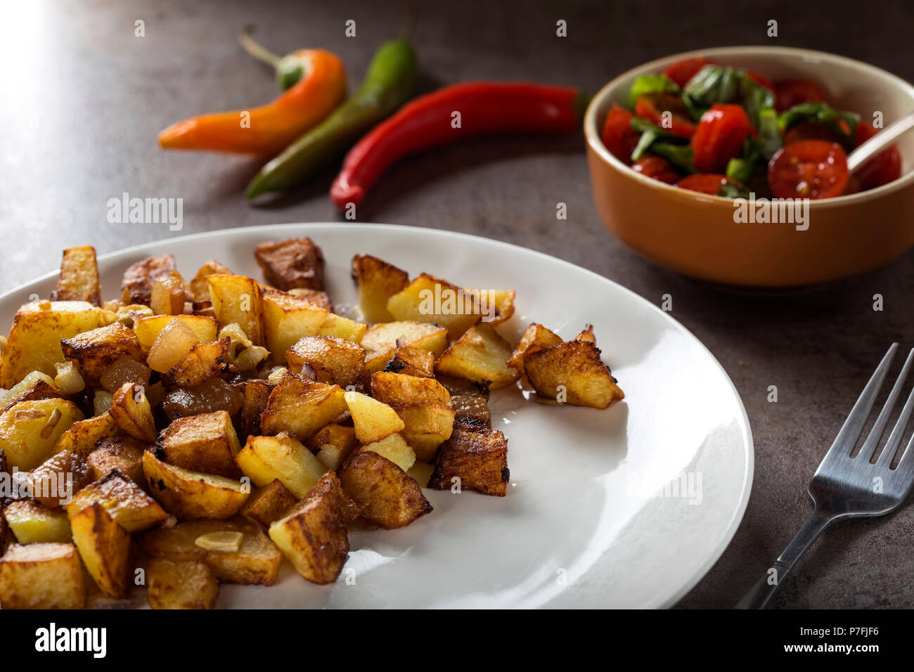 Pommes Frites mit kleinen Stücken des fettes Schwein Fleisch, Zwiebel und Knoblauch auf Platte Stockfoto