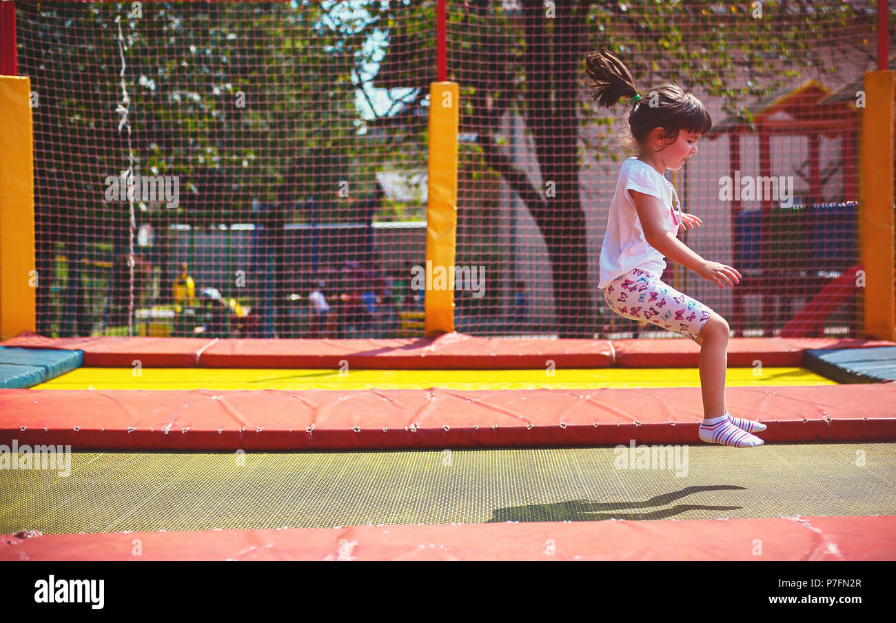 Kleines Mädchen auf dem Spielplatz im Park, Springen auf einem Trampolin. Stockfoto