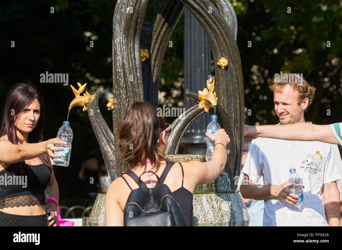 Touristen füllen Flaschen mit Wasser aus dem Brunnen außerhalb der U-Bahnstation Green Park, London, UK, während der Juli 2018 Hitzewelle mit Temperaturen um die 30 Grad Stockfoto