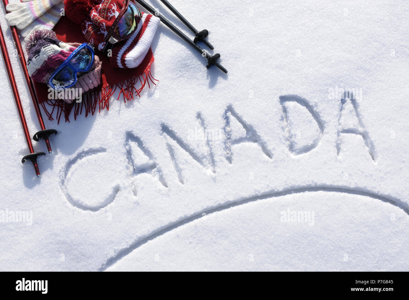 Das Wort Kanada im Schnee mit Ski Stöcke, Schutzbrille und Hüte geschrieben. Stockfoto