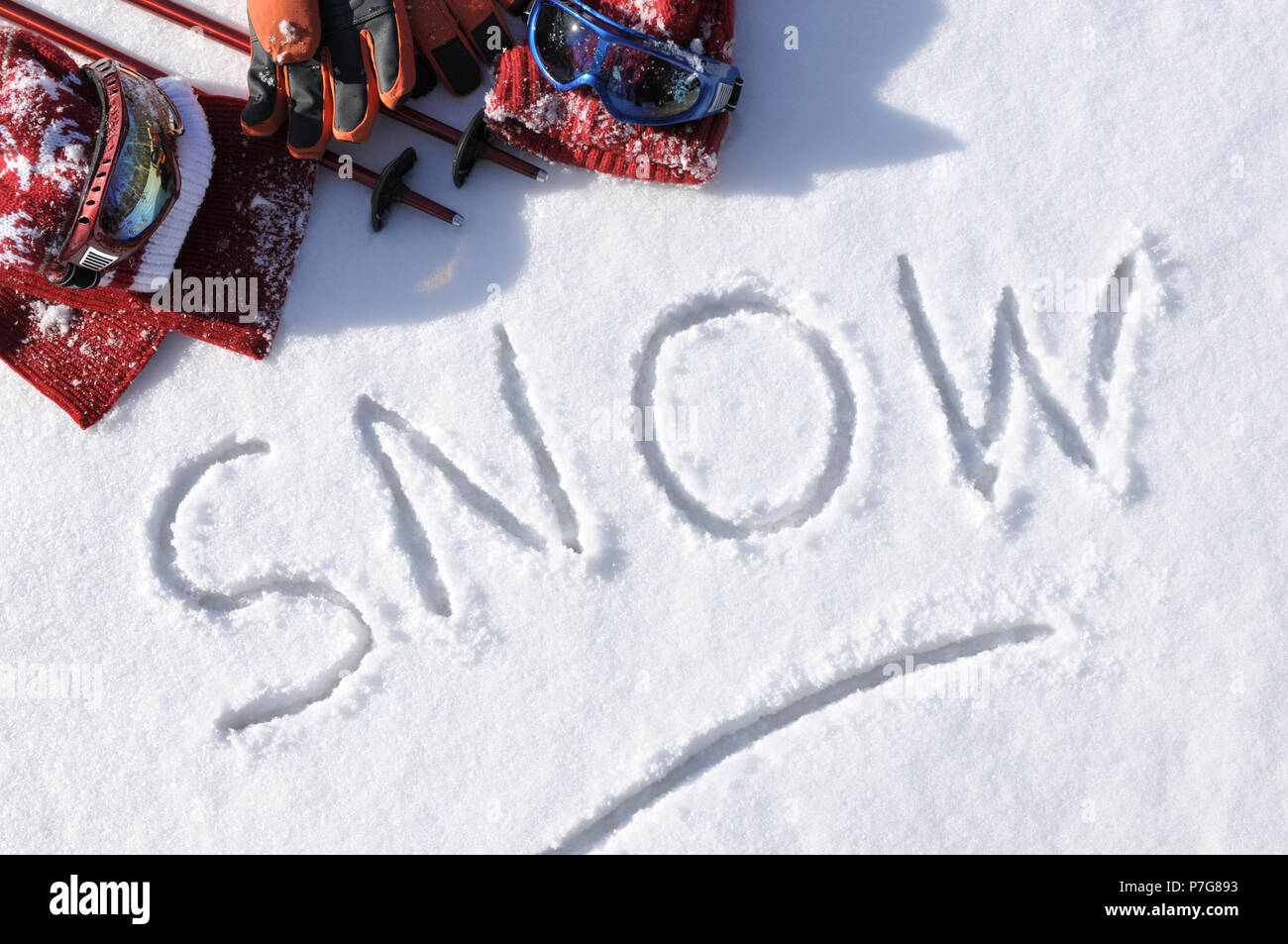 Das Wort Schnee im Schnee mit Ski Stöcke, Schutzbrille und Hüte geschrieben. Stockfoto