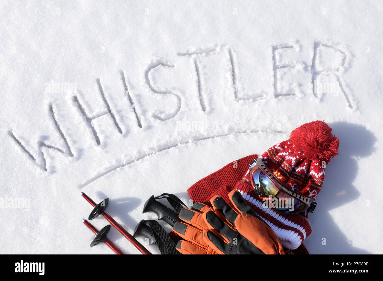 Das Wort Whistler im Schnee mit Ski Stöcke, Schutzbrille und Hüte geschrieben. Stockfoto