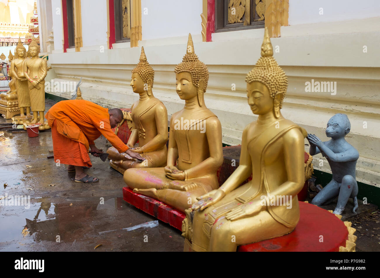 Buddhistischer Mönch Reinigung Buddha Statuen am Wat Pha That Luang Temple, Vientiane, Laos, Asien. Stockfoto