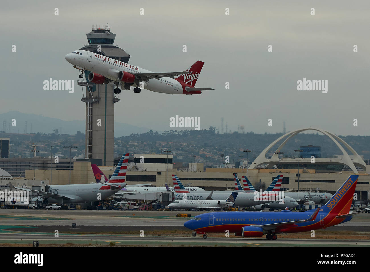 Virgin America Airbus A320 weg vom internationalen Flughafen von Los Angeles, LAX, bei Sonnenaufgang. Die ATC-Turm hinter sich. Stockfoto