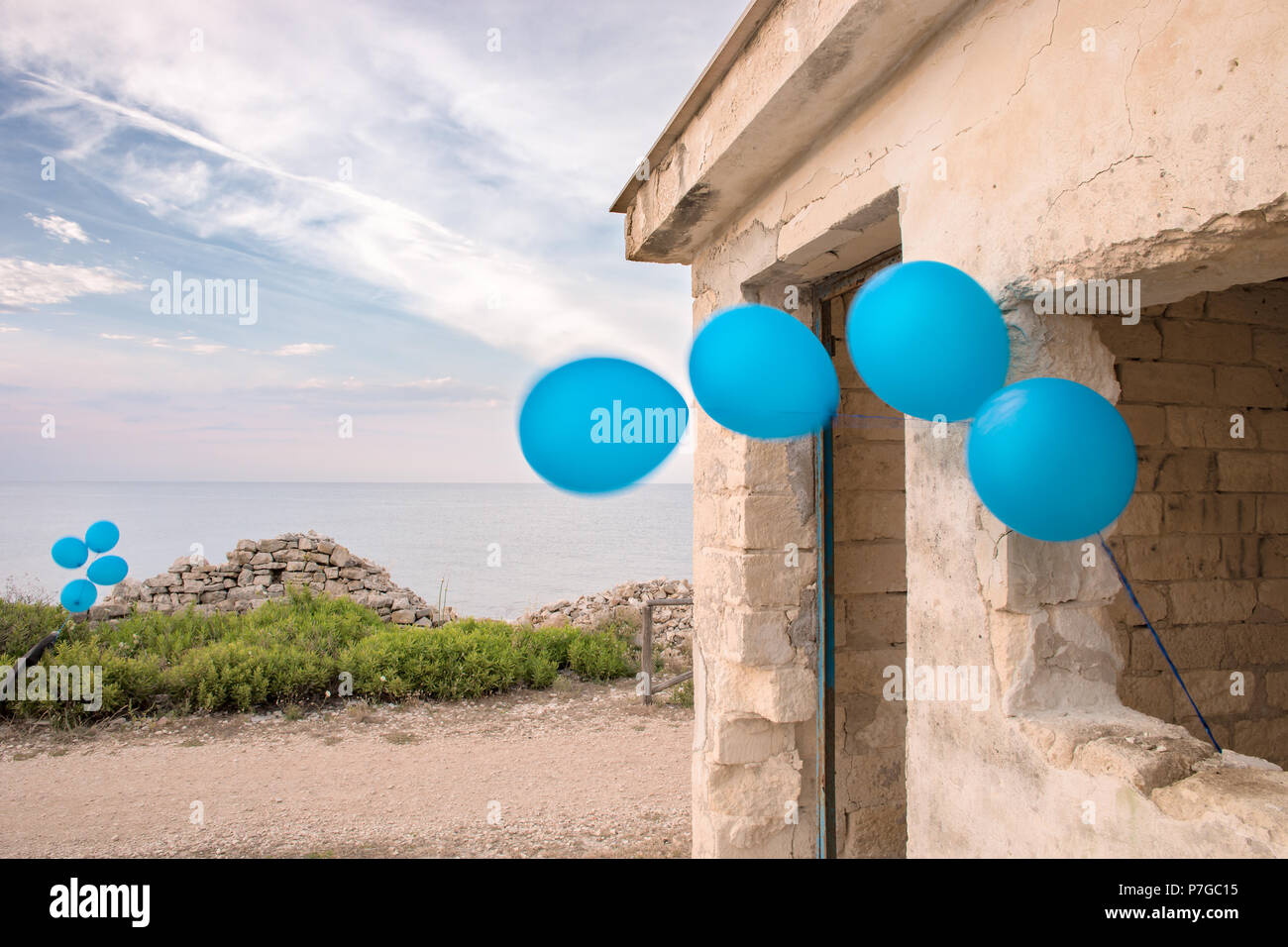 Blaue Luftballons gebunden auf einem zerstörten Haus mit Marine Stockfoto