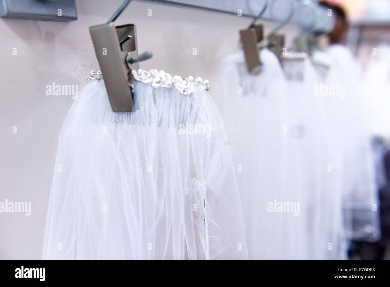 Viele Hochzeit Schleier in Boutique Diskontgeschäft, weiße Kleider hängen an Rack Kleiderbügel Reihe Nahaufnahme mit weißer Spitze, Tüll, Design Stockfoto