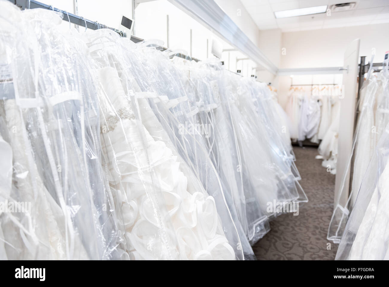 Viele brautkleider abendkleider in Boutique Diskontgeschäft, weiße Kleider hängen an Rack Kleiderbügel Reihe Nahaufnahme mit weißer Spitze, Tüll, Design Stockfoto