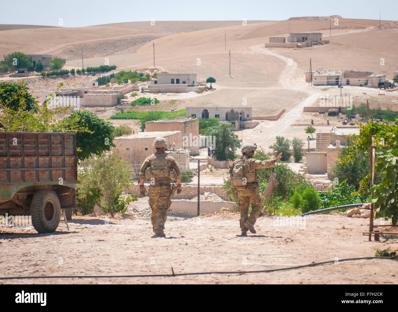 Us-Soldaten wave zu den Einheimischen, da sie eine unabhängige durchführen, koordiniert Patrouille durch ein Dorf in der Nähe von Manbij, Syrien, 26. Juni 2018. Die Patrouillen werden in Abstimmung mit der türkischen Streitkräfte auf beiden Seiten der Demarkationslinie getan, um die Sicherheit und die Stabilität in der Region zu gewährleisten. (U.S. Armee Foto: Staff Sgt. Timothy R. Koster) Stockfoto