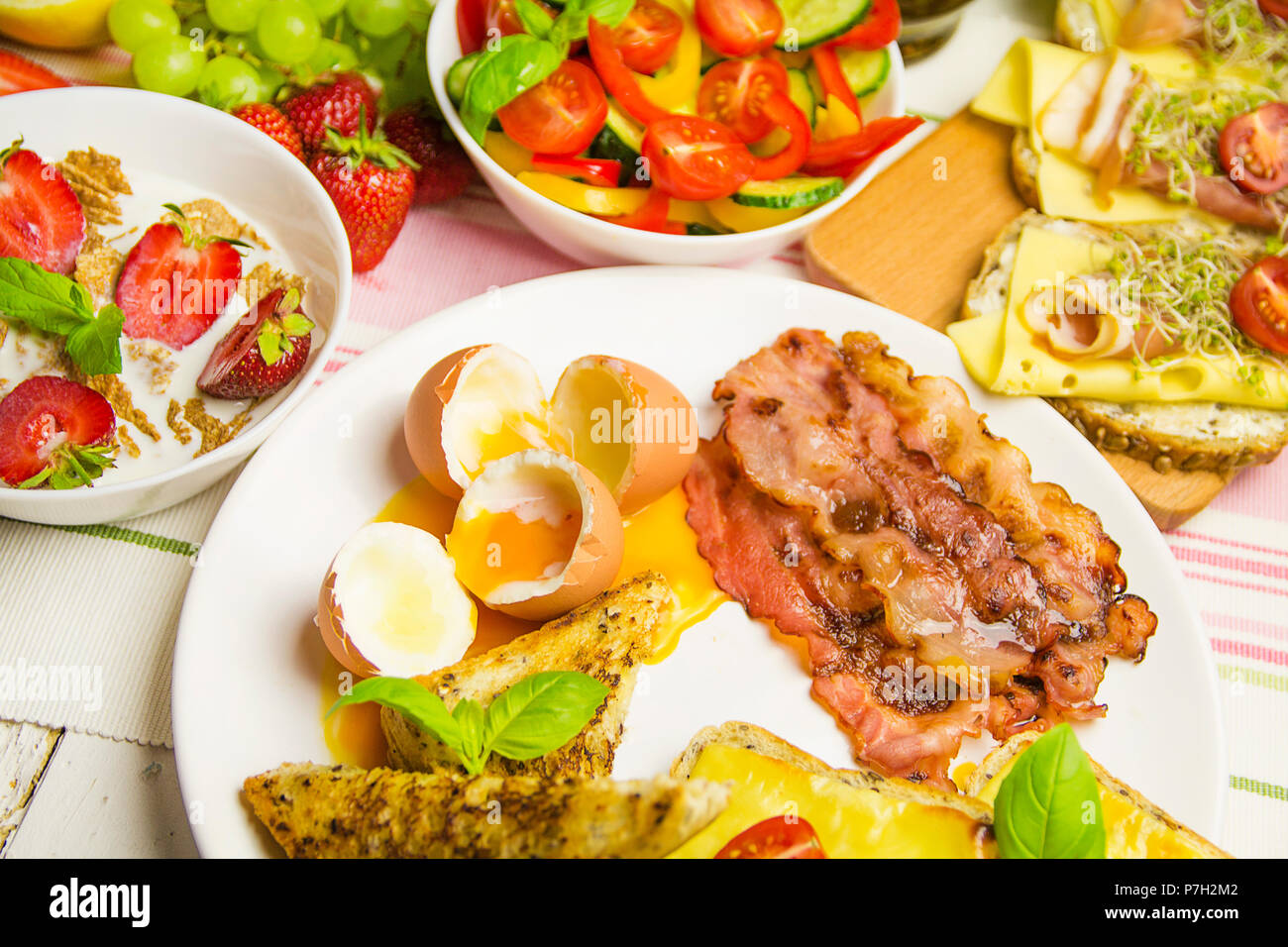 Das Frühstück auf dem Tisch mit Eiern, Speck, Sandwiches und Obst Stockfoto