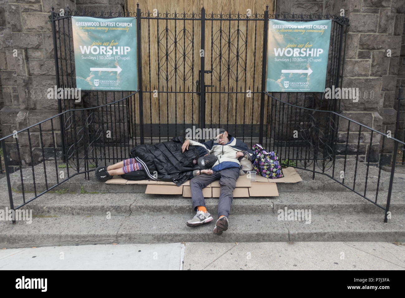 Mann und Frau schlafen tief und fest in den frühen Morgenstunden vor einer baptistischen Kirche entlang der 7. Avenue in Park Slope, Brooklyn, New York. Stockfoto