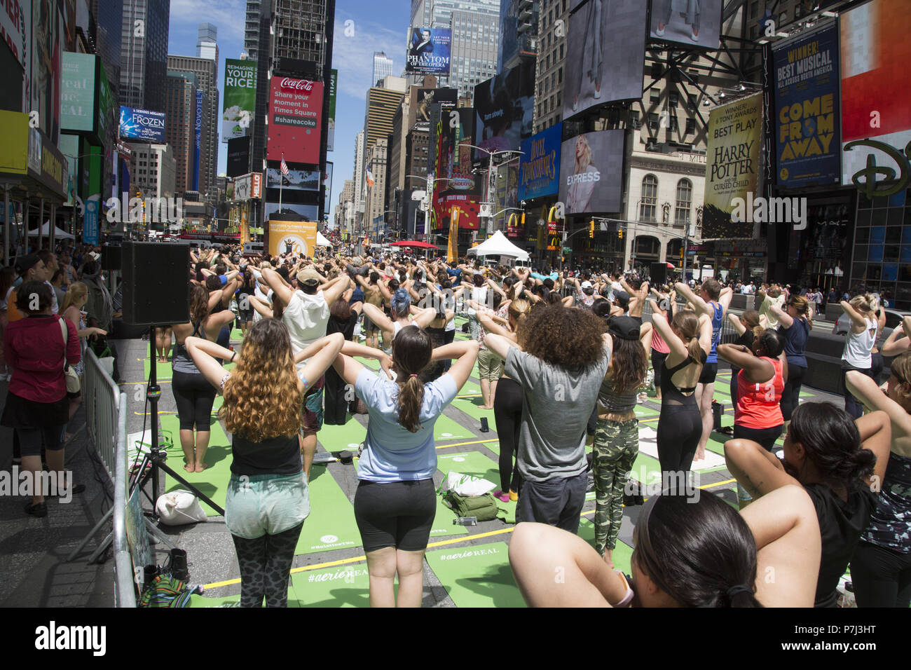 Yoga Enthusiasten nehmen kostenlose Kurse in den jährlichen Times Square Sommersonnenwende Feier mit Klassen den ganzen Tag inmitten der Material glitz der Nachbarschaft, New York City. Stockfoto