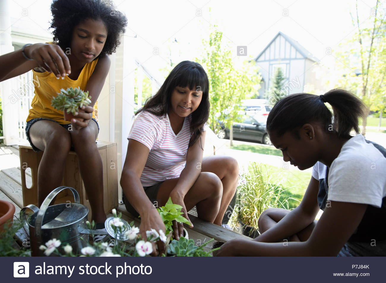 Mutter und tween Töchter Gartenbau, Blumen Pflanzen auf der Vorderseite stoop Stockfoto