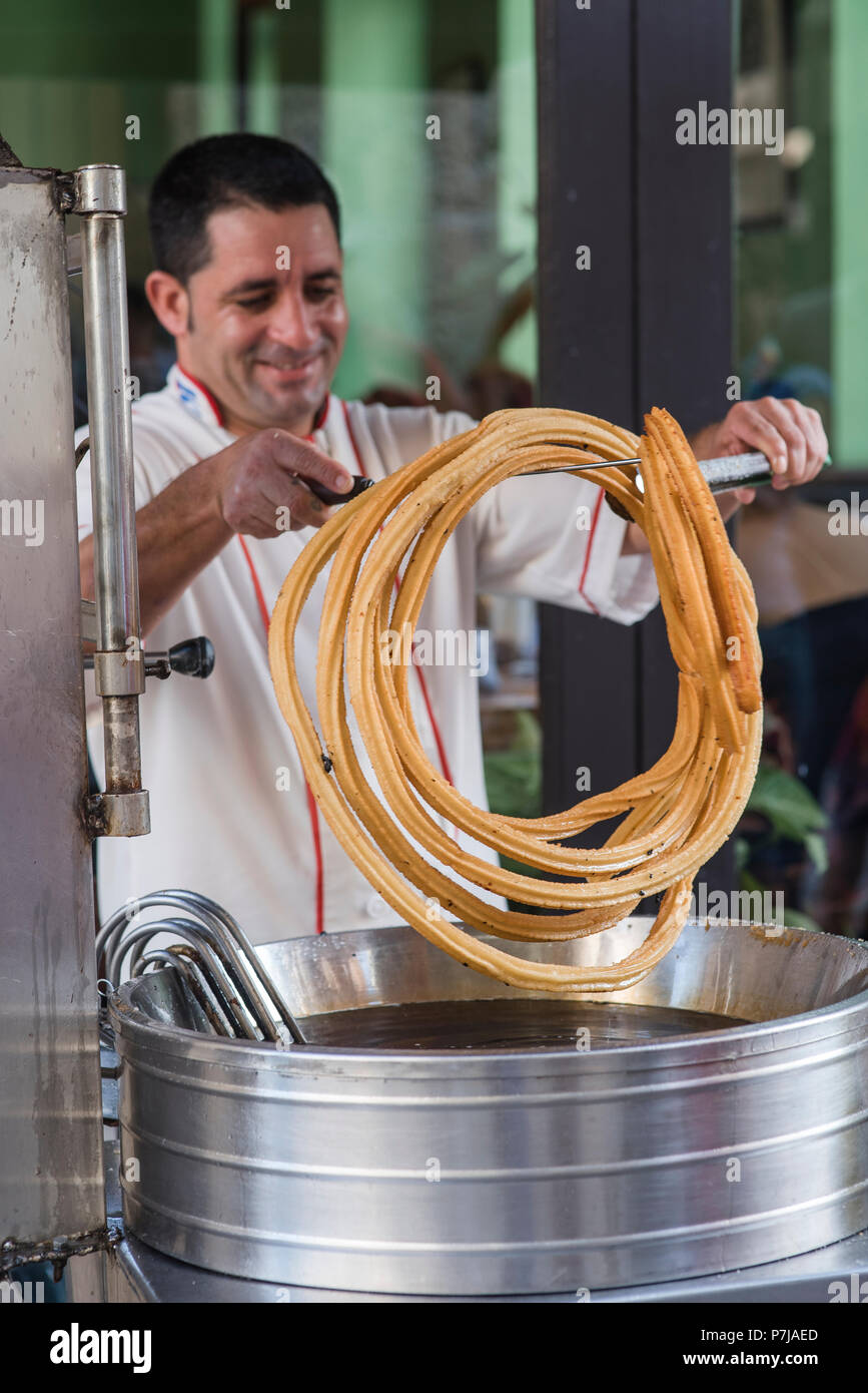 Genießen Sie ein frisch gebratenes Churro an einer Straßenecke in Havanna, Kuba. Stockfoto