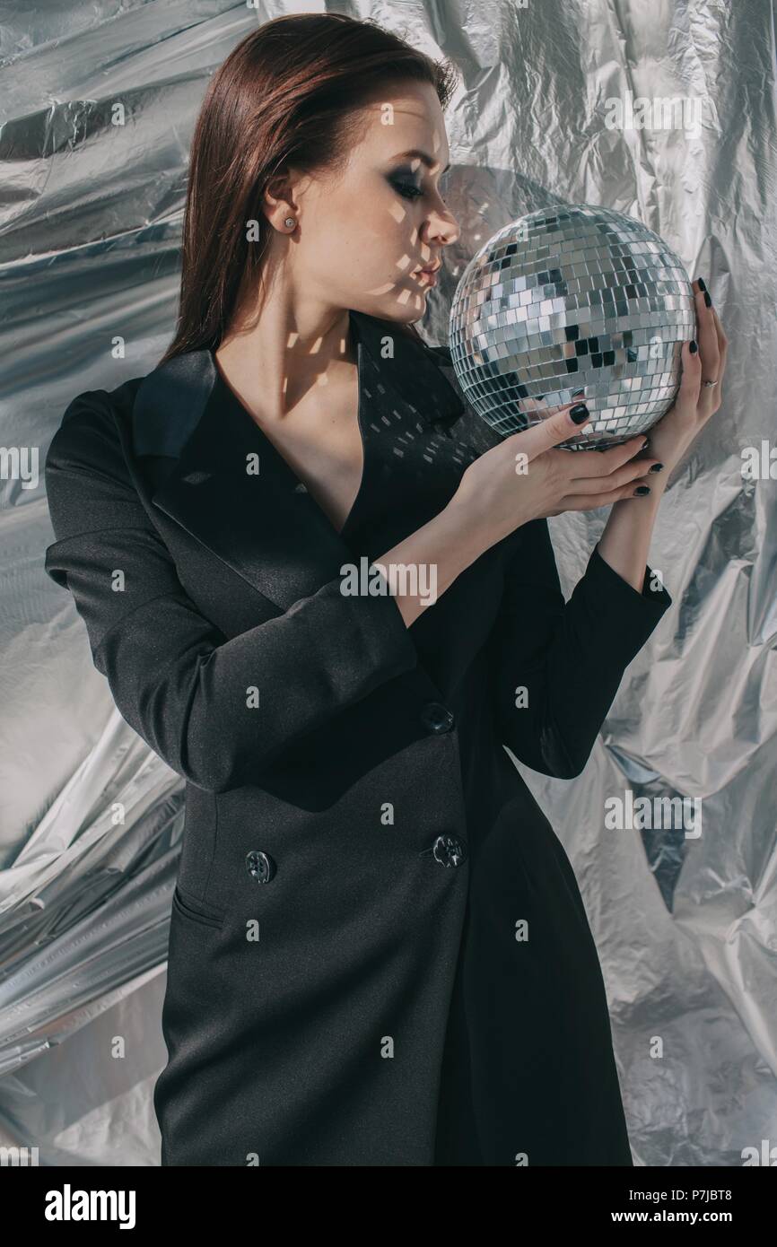 Portrait von einer Frau mit einem silbernen Disco ball vor ihrem Gesicht Stockfoto