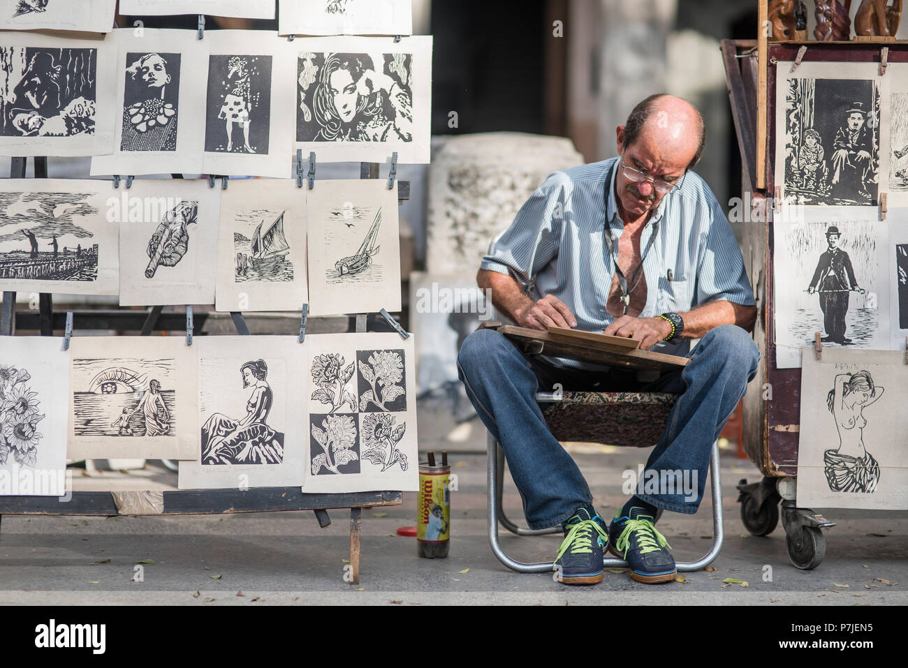 Ein kubanischer Künstler arbeitet auf seine Ausdrucke in einer freien Markt in Havanna. Stockfoto