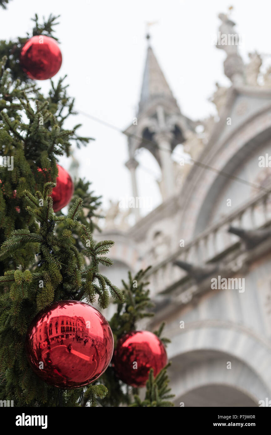 Details zu ein Weihnachtsbaum in Venedig mit historischen Fassaden im Hintergrund, in den roten Christbaum Kugeln wider Stockfoto