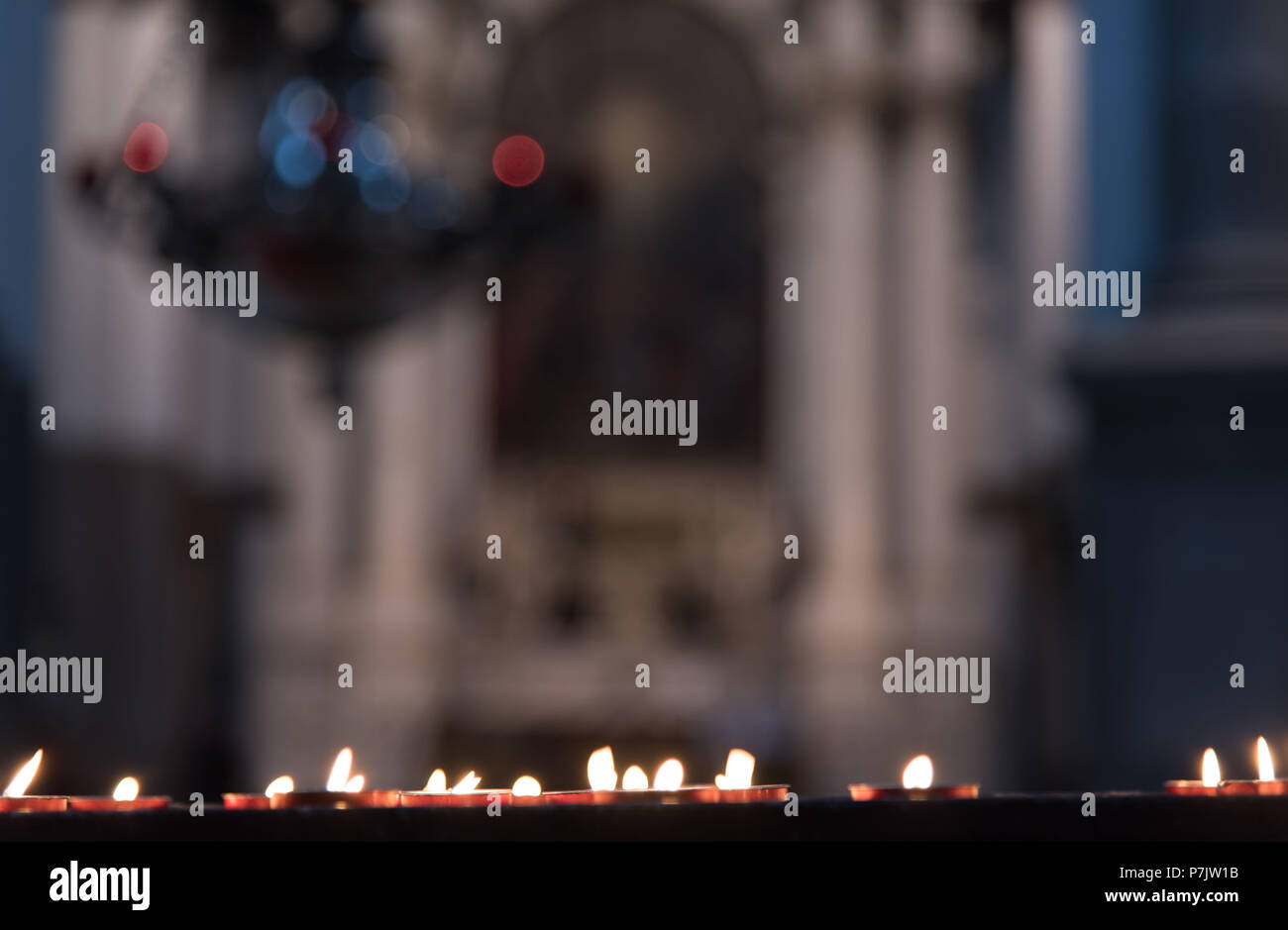 Brennende Kerzen in der Basilika di Santa Maria della Salute, Venedig, Kronleuchter im Hintergrund Stockfoto