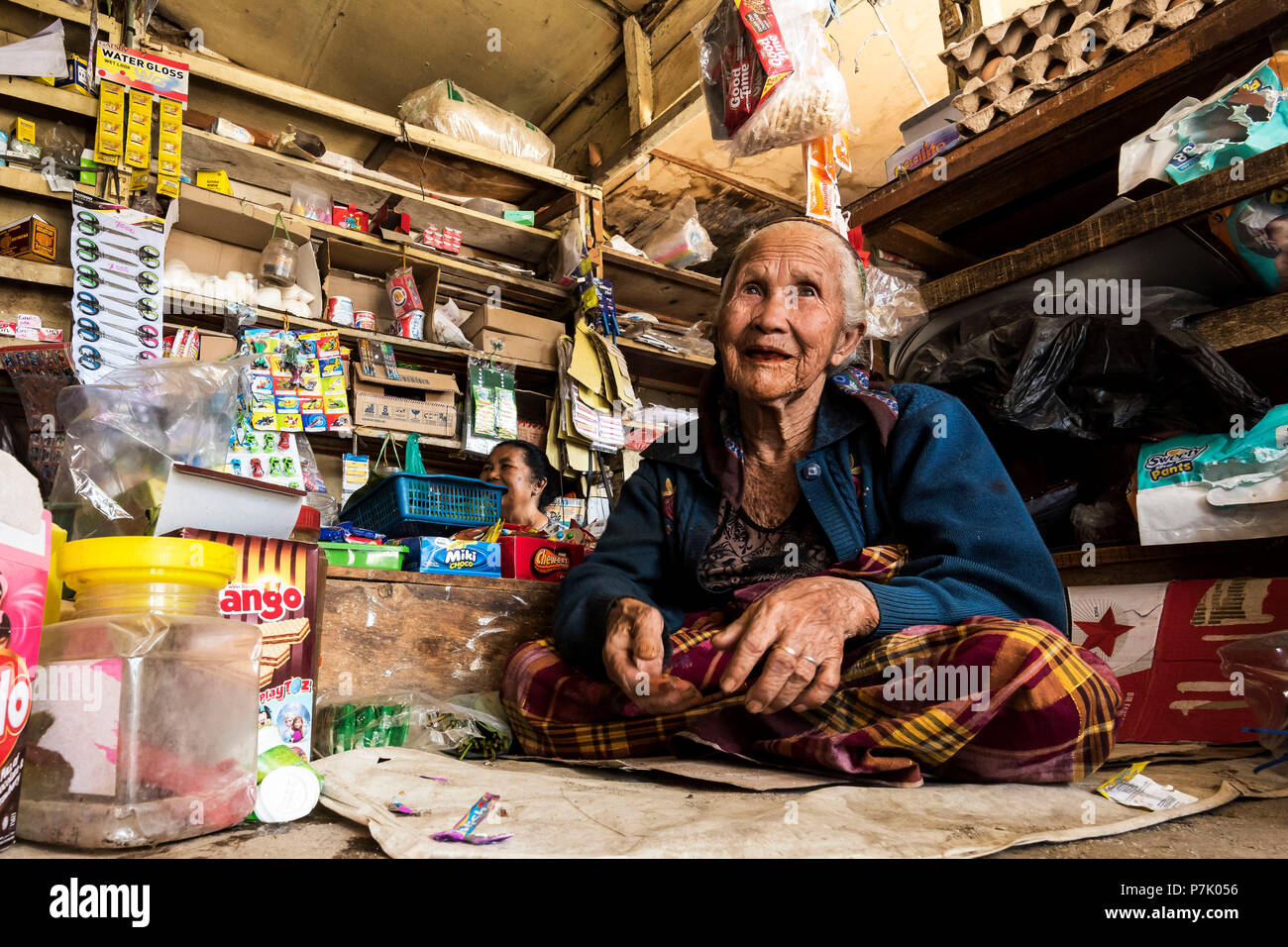 Alte Batak Frau in eine verwirrende Dorfladen eines Batak Dorf sitzen, Stockfoto