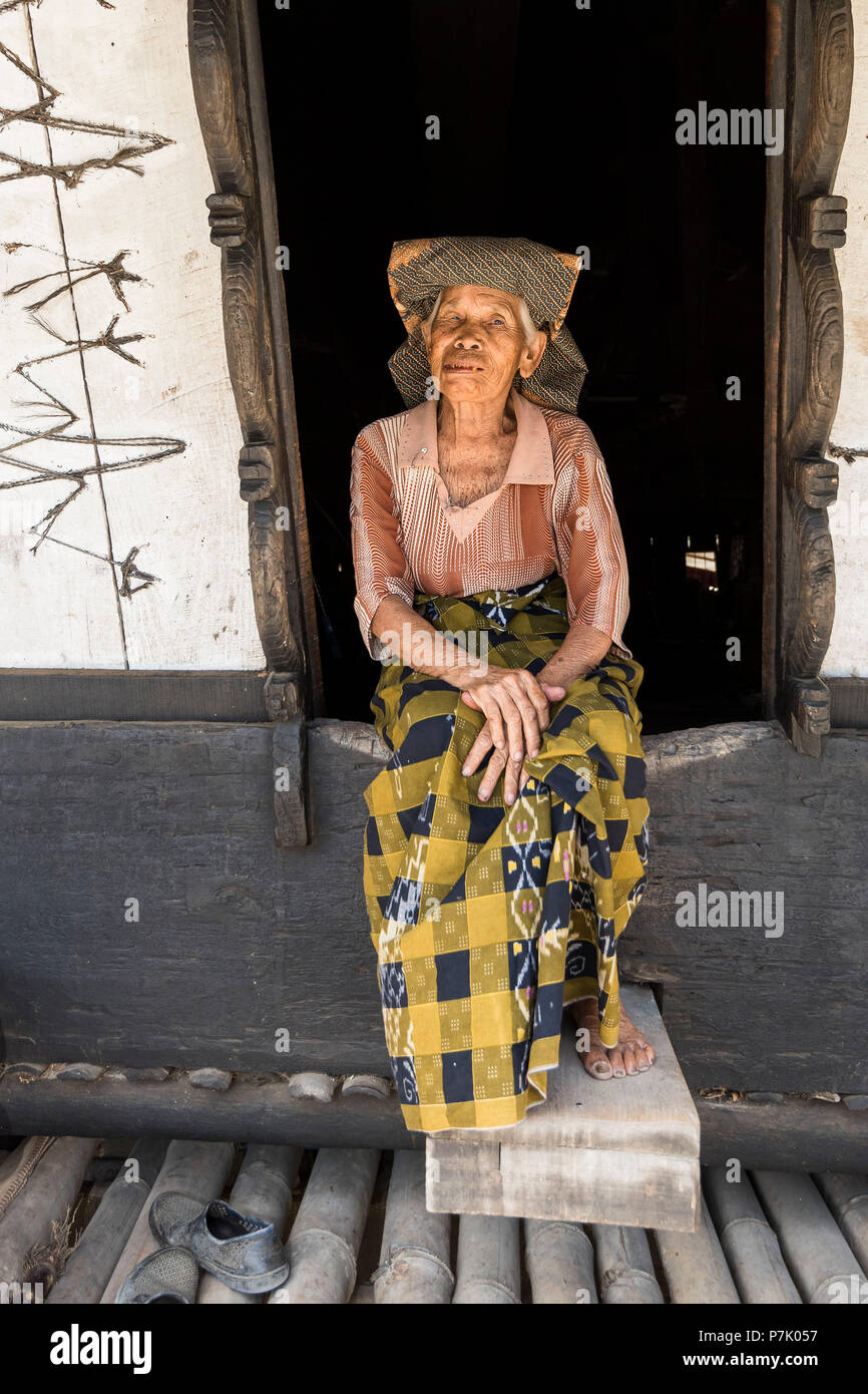 Eine alte Batak Frau sitzt im Eingangsbereich ein traditionelles Haus in der Nähe von Lake Toba Batak Stockfoto