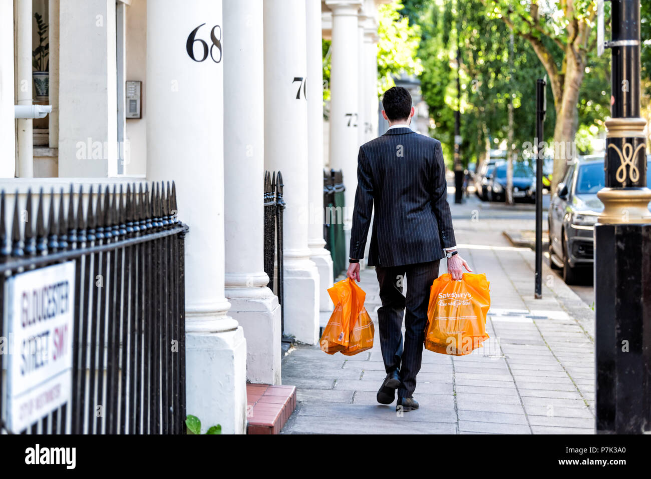 London, Großbritannien, 22. Juni 2018: Nachbarschaft Stadtteil Pimlico, Gloucester Street, Geschäftsmann Mann einkaufen Taschen nach der Arbeit am Abend Stockfoto
