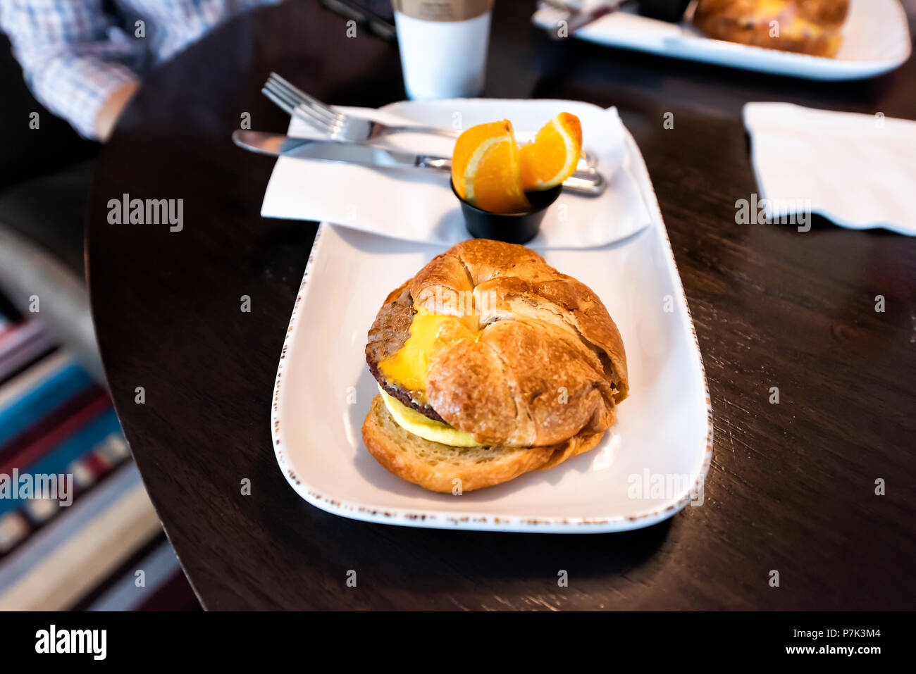 Nahaufnahme von herzhaften Frühstück croissant Sandwich gelb Dessert in Bäckerei, Shop, Cafe, speichern Tabelle auf Platte mit Wurst, Käse, Orangenscheiben f Stockfoto
