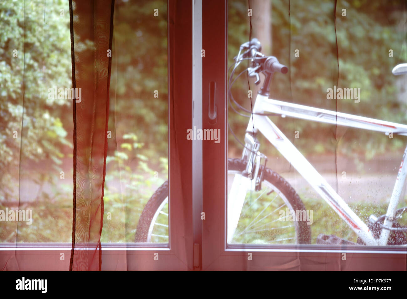 Ein Mountainbike hinter dem Vorhang eines Fensters Stockfoto