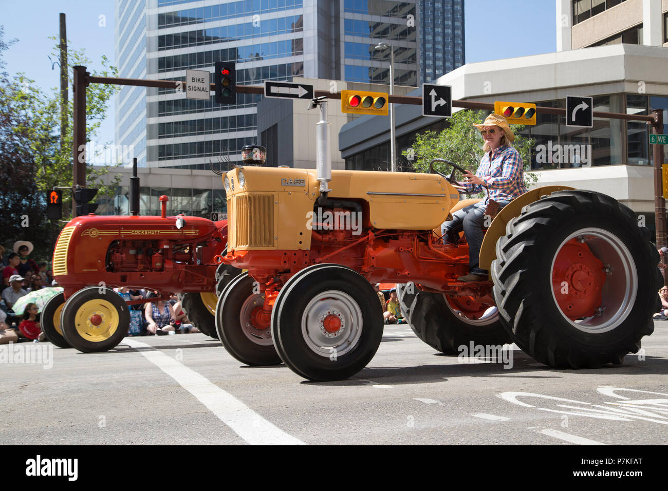Frau fährt in der Calgary Stampede Parade mit einem Oldtimer-Traktor. Die Parade durch die Innenstadt startet jedes Jahr die Calgary Stampede. Rosanne Tackaberry/Alamy Live News Stockfoto
