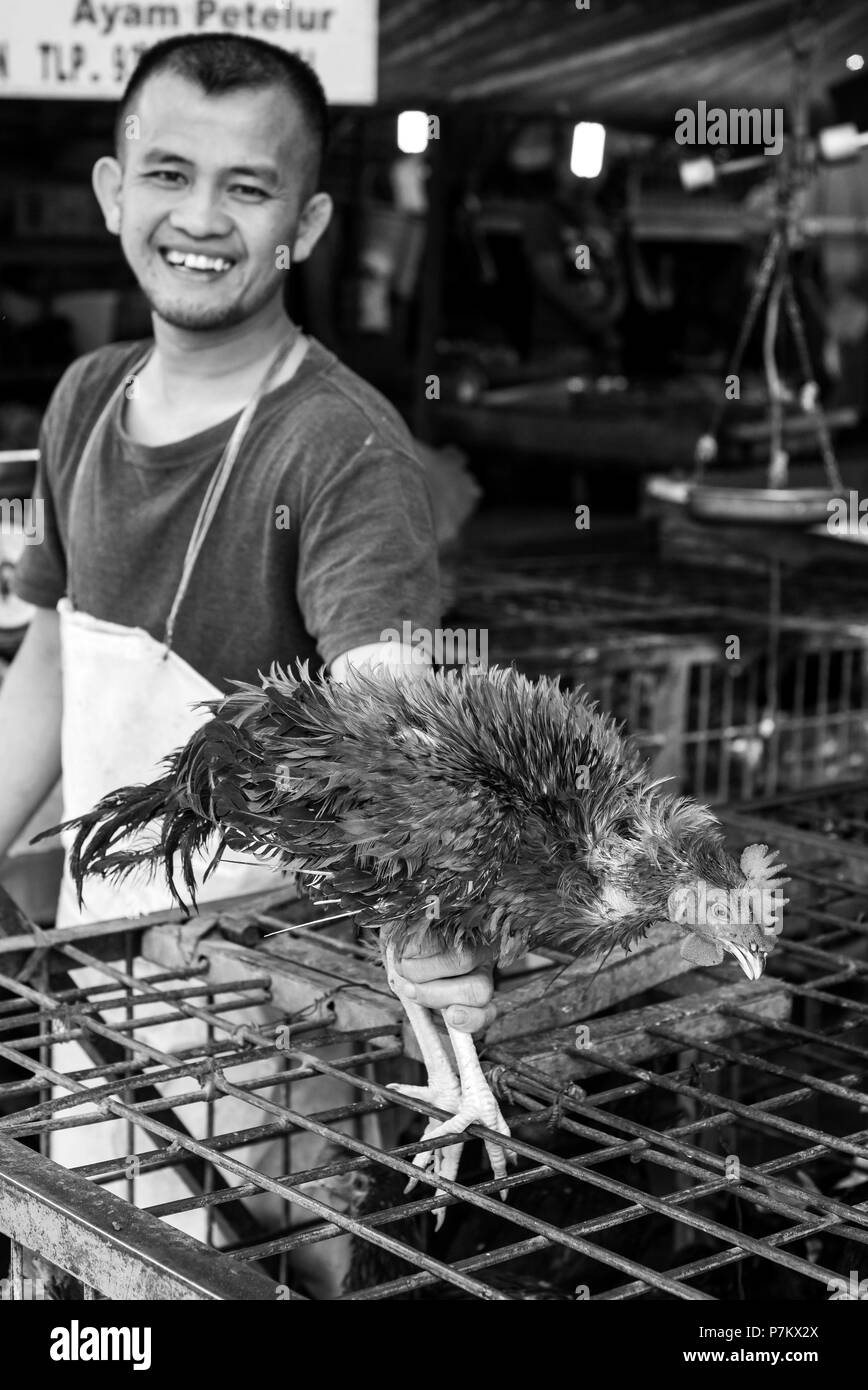 Lachend Metzger mit einem Huhn in der Hand Stockfoto