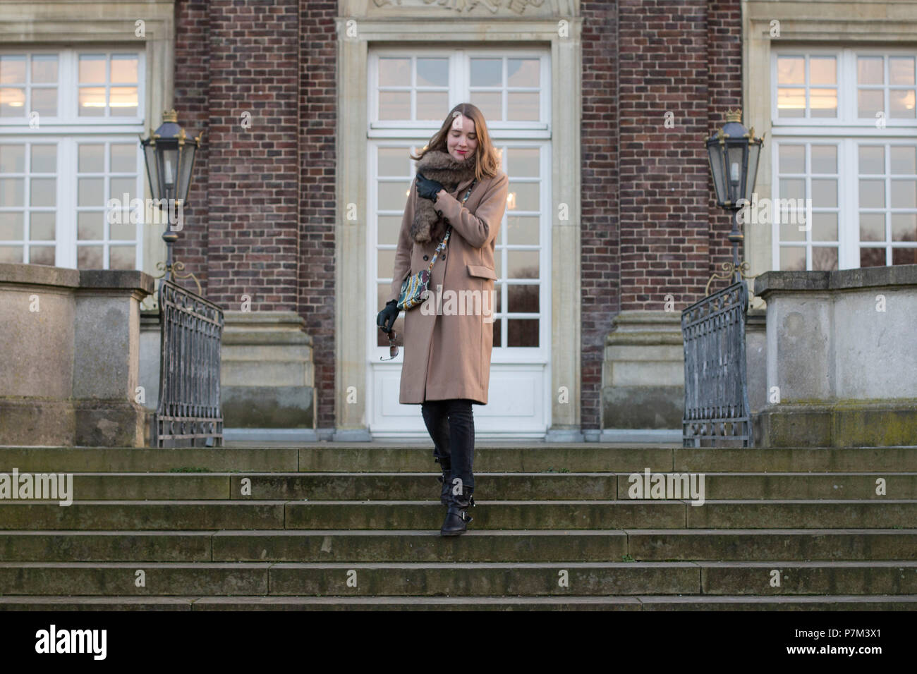 Junge Frau mit einem Mantel unten gehen eine Treppe Stockfoto